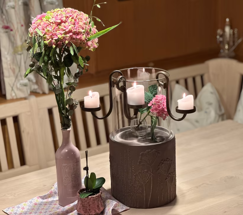 Blumenstrauß und Kerzen auf Holztisch