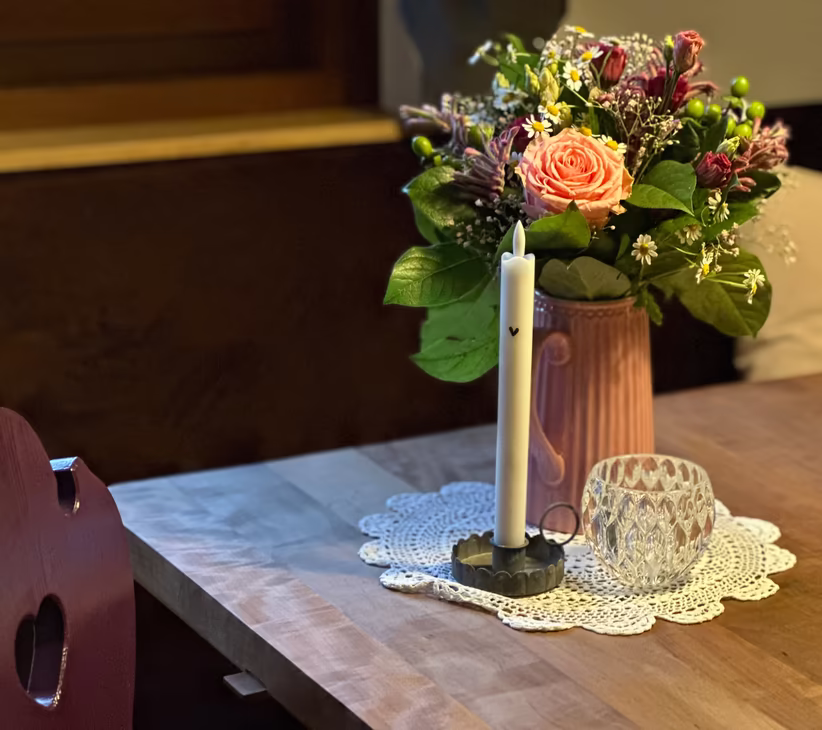 Blumenstrauß und Kerze auf Holztisch